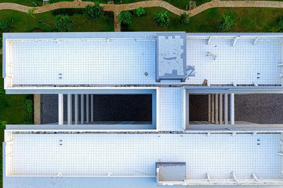 Top-down view of a white flat roof with raised parapet edges and roof hatches
